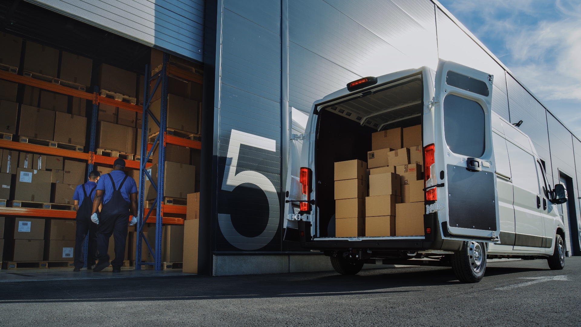 Außerhalb des Lagers von Logistics Distributions: Zwei Arbeiter laden D